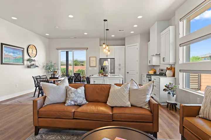 Open-concept living area featuring wood-finish flooring, recessed lighting, and a white kitchen with stainless steel appliances