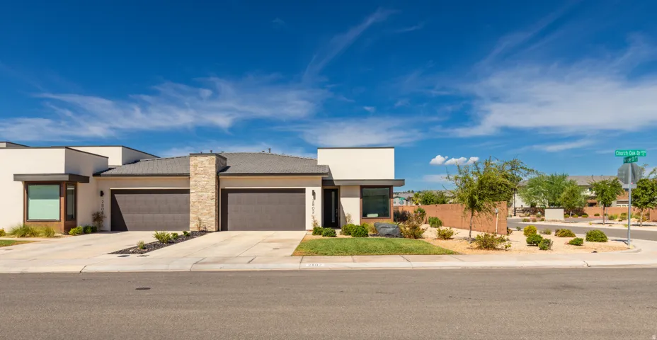 Contemporary stucco exterior with stone accents, two-car garage, and desert-inspired landscaping