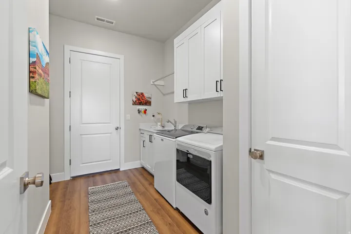 Built-in white cabinetry, wood-finish flooring, and a utility sink