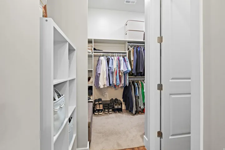 Built-in shelving, hanging rods, and carpeted flooring