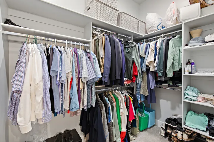 Custom closet organization system featuring multiple hanging rods, built-in shelving, and a carpeted floor