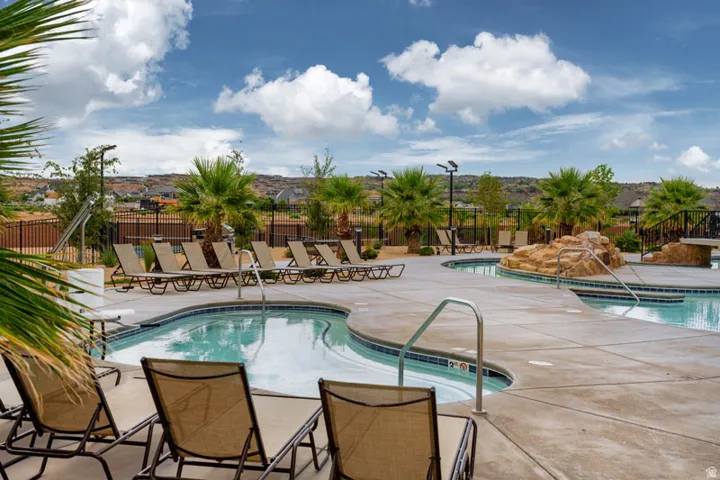 Expansive outdoor pool area featuring a curved pool, integrated spa, and rock waterfall feature