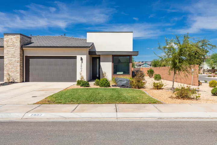 Modern exterior featuring a stacked stone accent wall, a dark gray garage door, and a flat roof design