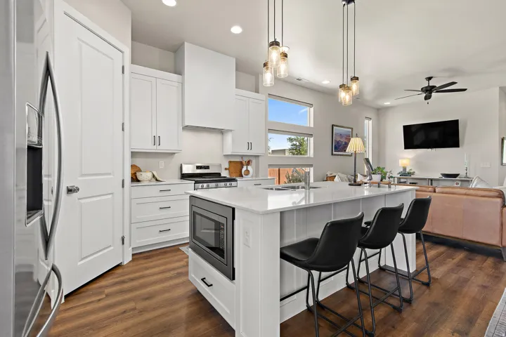 Contemporary kitchen featuring white cabinetry, stainless steel appliances, a center island with bar seating, and wood-finish flooring