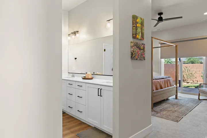 Dual sink vanity with white cabinetry and dark hardware, wood-finish flooring, recessed lighting, and a contemporary ceiling fan