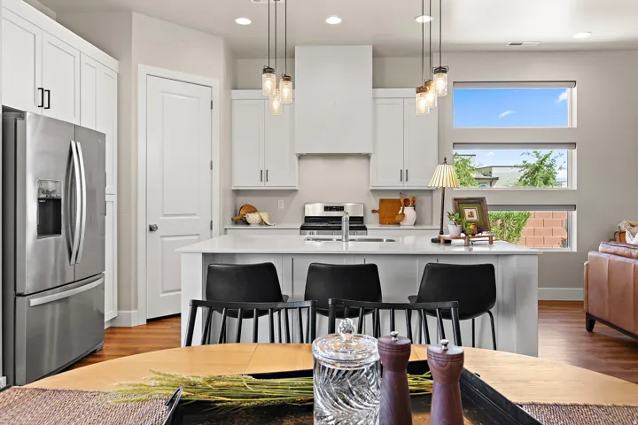 Modern kitchen featuring white cabinetry, a stainless steel refrigerator, white countertops, and a kitchen island with seating