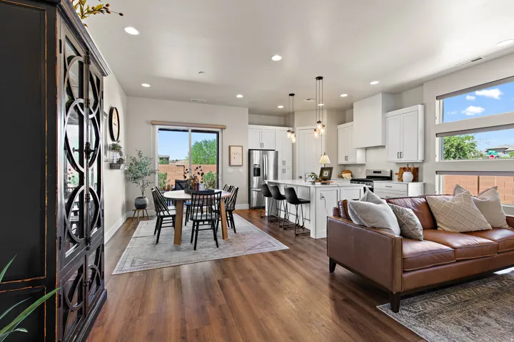 Open-concept living area with wood-finish flooring, white kitchen cabinetry, recessed lighting, and a sliding glass door