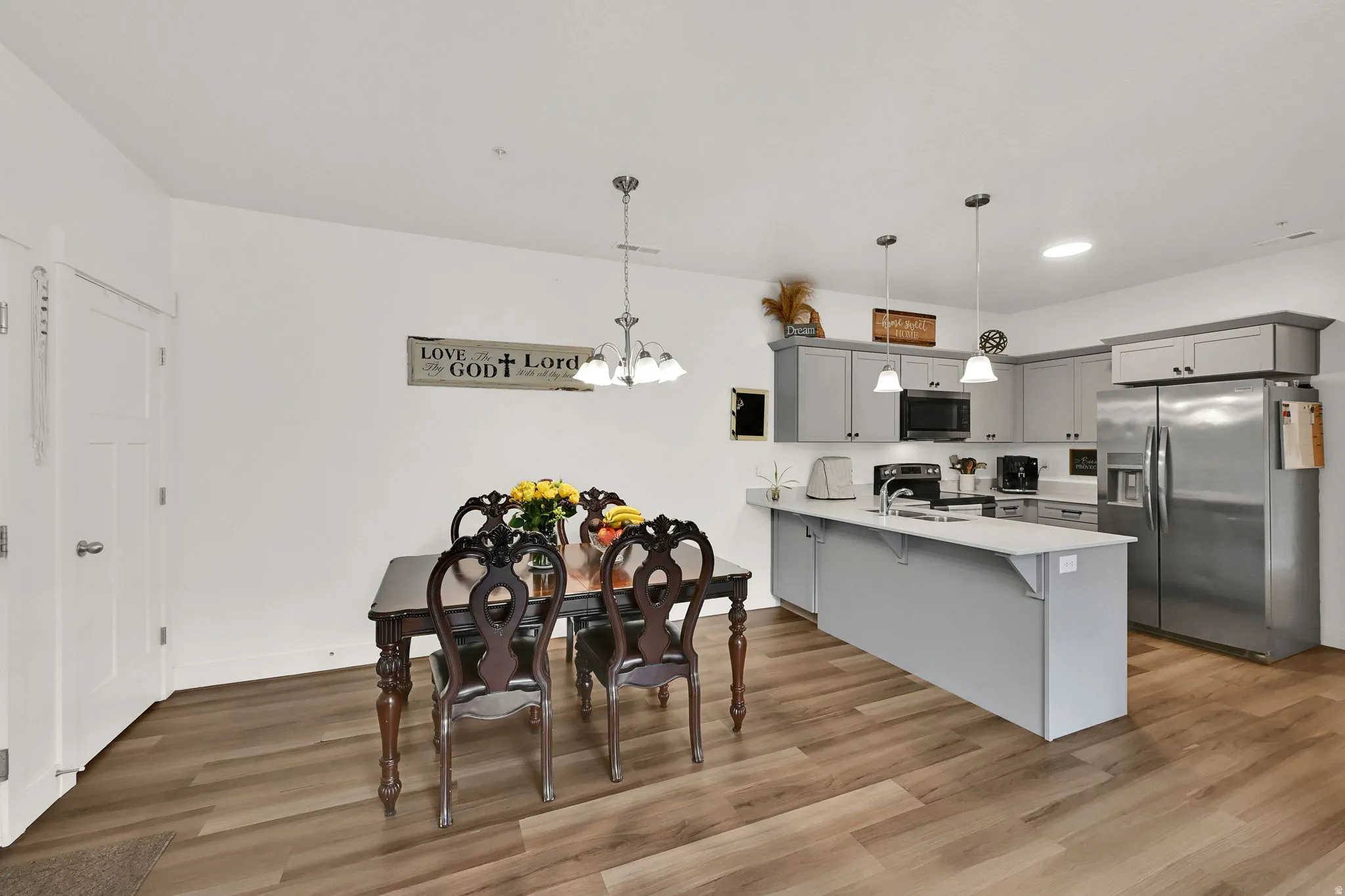 Open-concept kitchen and dining area featuring LVP flooring, recessed lighting, pendant lighting, and an island with an undermount sink