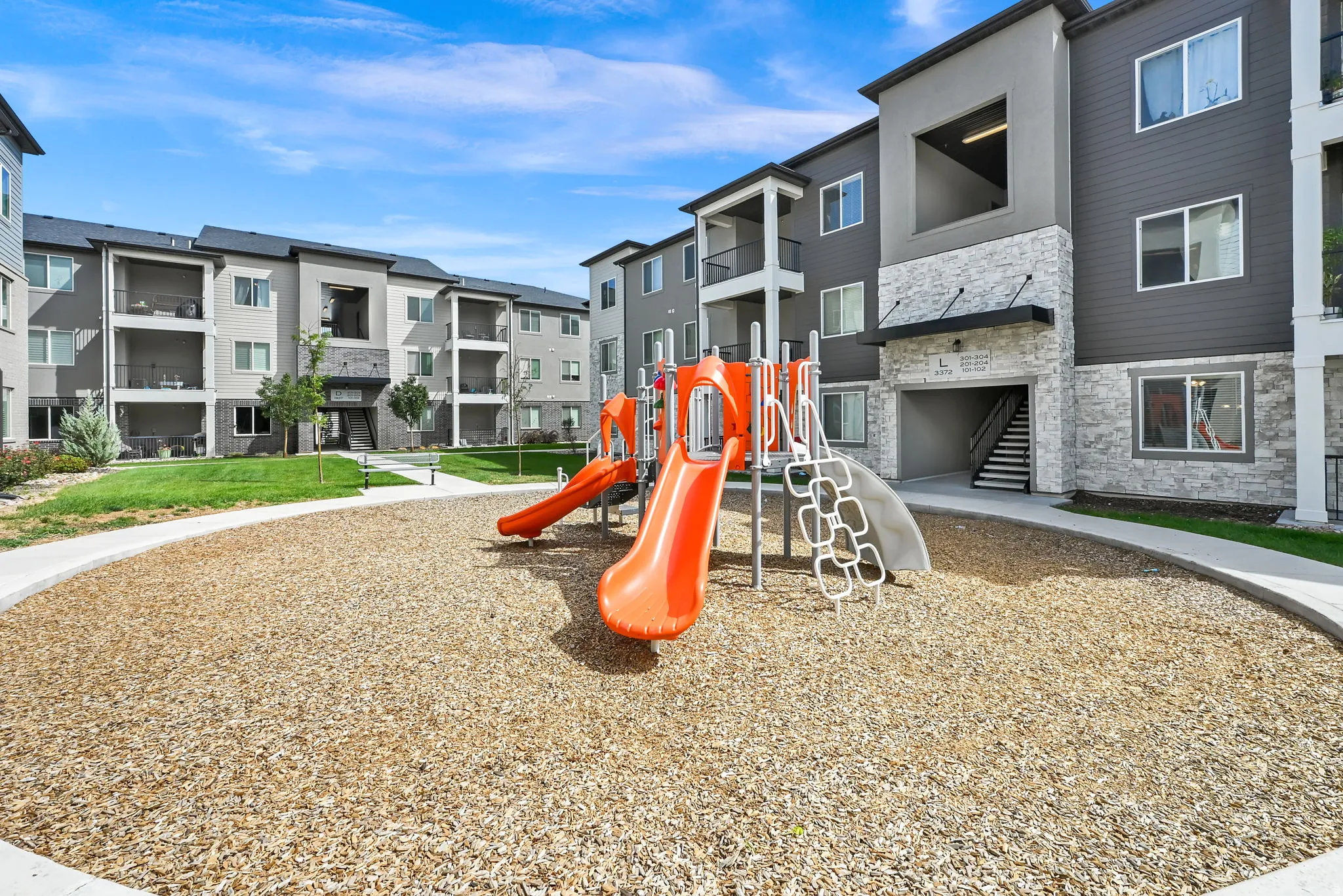 Outdoor play structure with slides and climbing features, surrounded by wood chip surfacing
