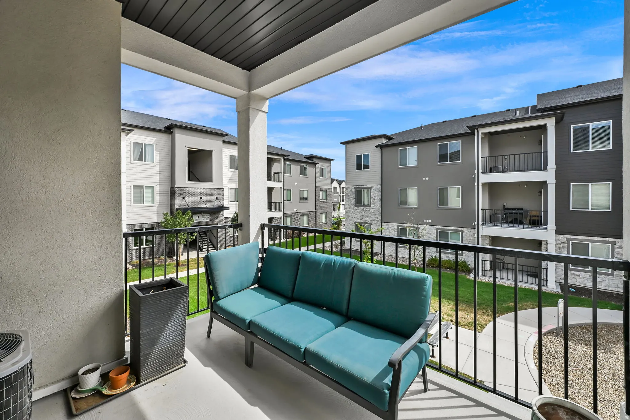 Private balcony with a painted concrete surface, supported by architectural columns, and featuring black metal railings