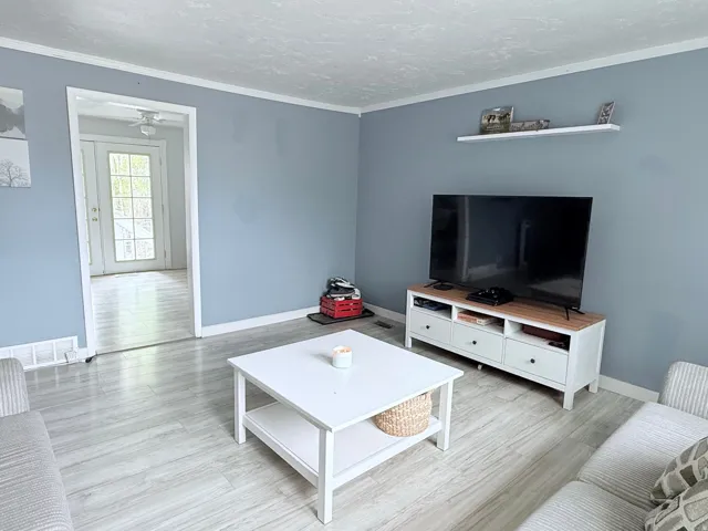 Light-toned wood-finish flooring throughout, ceiling-mounted light fixture, and a white floating shelf