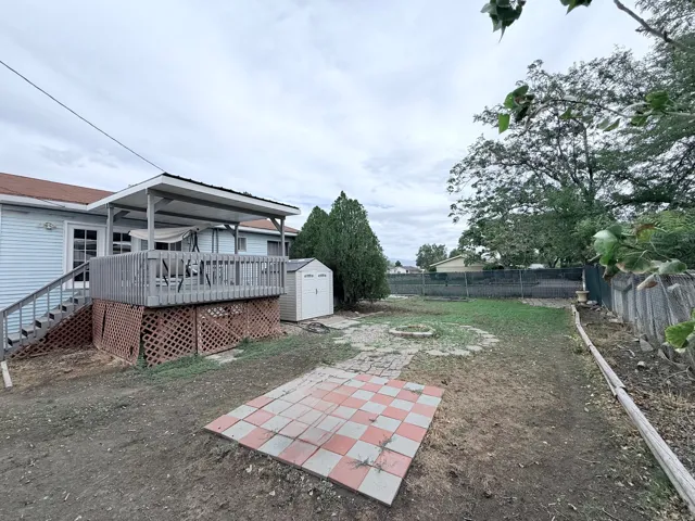 Rear deck with a covered patio, exterior siding, and a storage shed