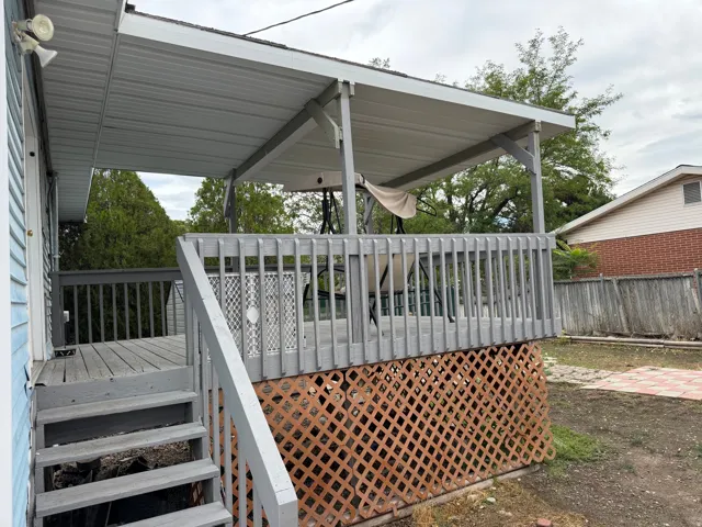 Elevated wood deck with a slatted railing, covered patio structure, and lattice skirting