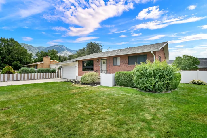 Brick exterior, attached garage, well-maintained landscaping, privacy fencing, mountain backdrop