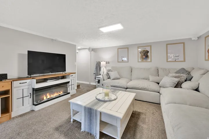 Built-in media console with a linear electric fireplace, wood-finish countertop, and storage cabinetry