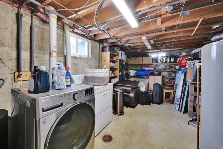 Concrete floor basement with exposed ceiling joists and utility piping