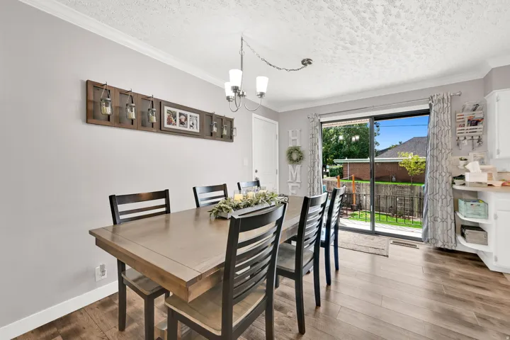 Wood-finish flooring, sliding glass door, crown molding, and a built-in kitchen cabinet with open shelving