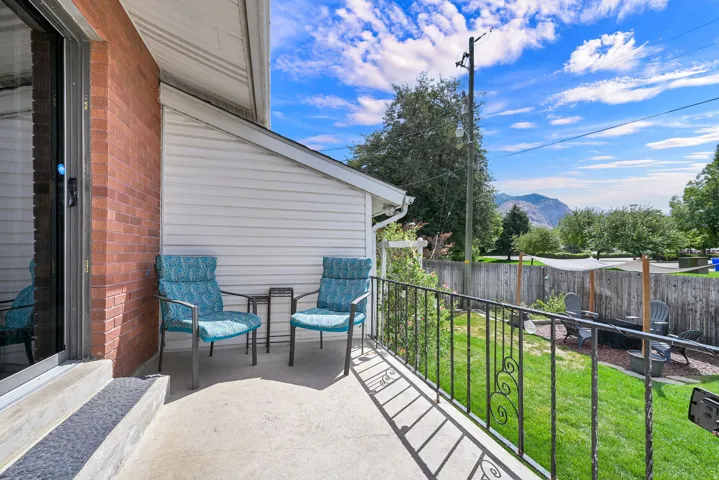 Paved patio with black wrought iron railing, brick exterior, and a sliding glass door