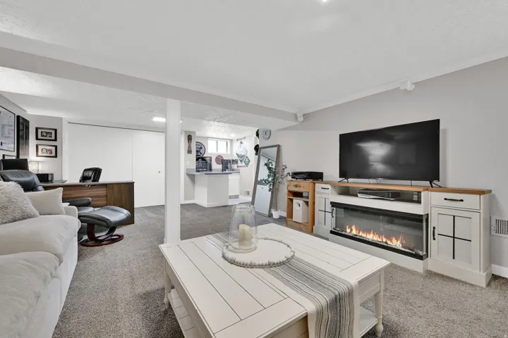 Recessed lighting, light gray carpeting, built-in entertainment center with an electric fireplace, white sliding closet doors, and a built-in bar