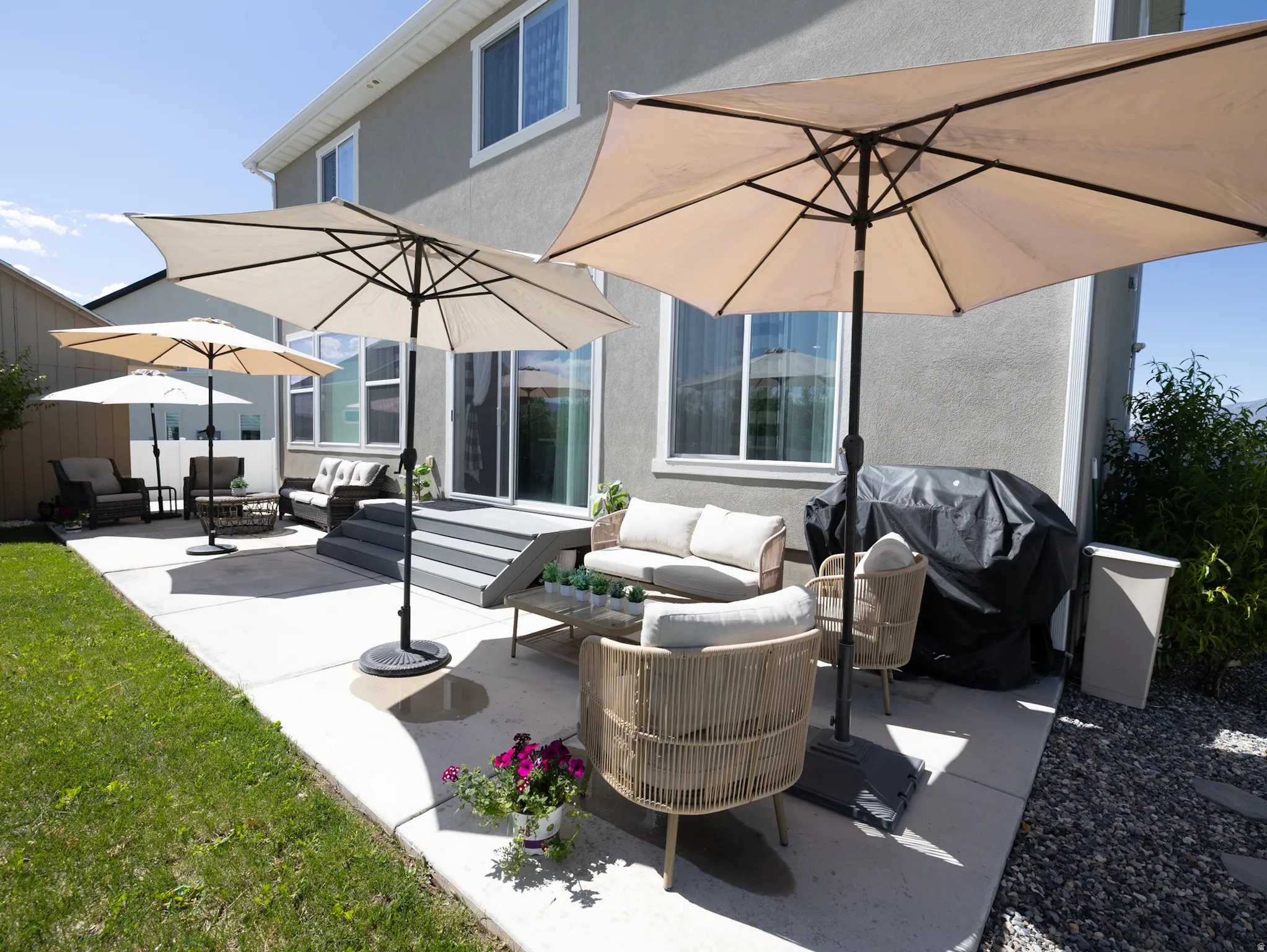 Exterior patio area featuring a concrete surface, a multi-tiered deck, sliding glass door access, and a stucco exterior finish