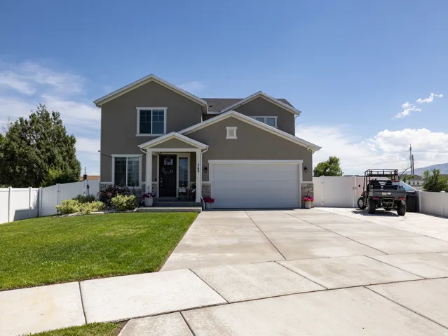 Two-story stucco exterior with stone accents, a covered entry, an attached two-car garage, and a concrete driveway