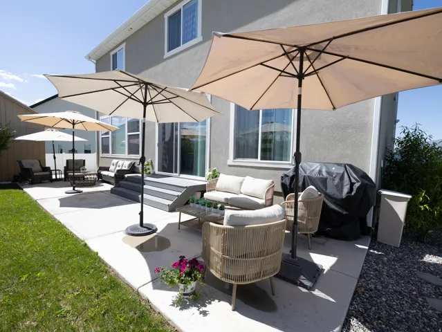 Exterior patio area featuring a concrete surface, a multi-tiered deck, sliding glass door access, and a stucco exterior finish