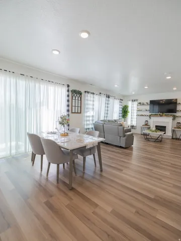 Open-concept living space featuring wood-finish flooring, recessed lighting, and a white fireplace with a mantel