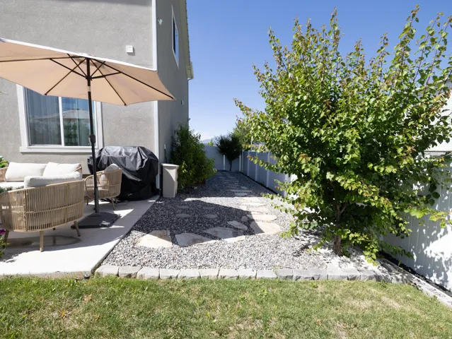 Paved patio area, gravel path with stepping stones, established landscaping, privacy fencing, stucco exterior