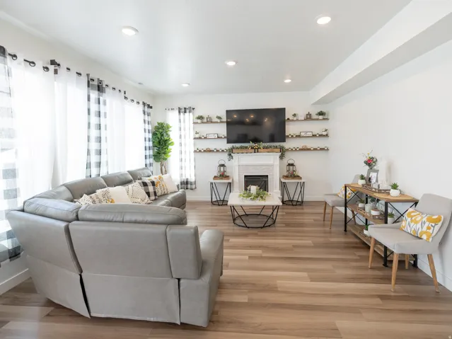 Recessed lighting, wood-finish flooring, white walls, built-in shelving, and a fireplace with a white mantel