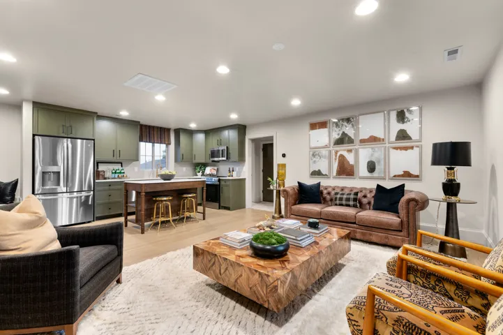 Open-concept living area featuring recessed lighting, wood-finish flooring, and a kitchen with olive green cabinetry, an island, and stainless steel appliances