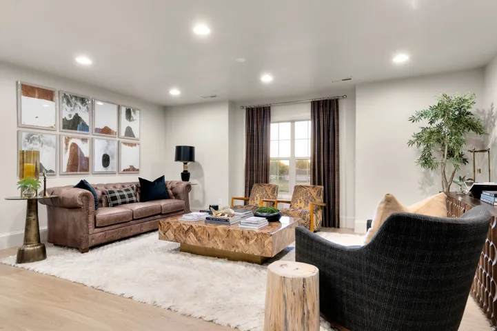 Recessed ceiling lighting, light wood-finish flooring, and a window with dark curtains