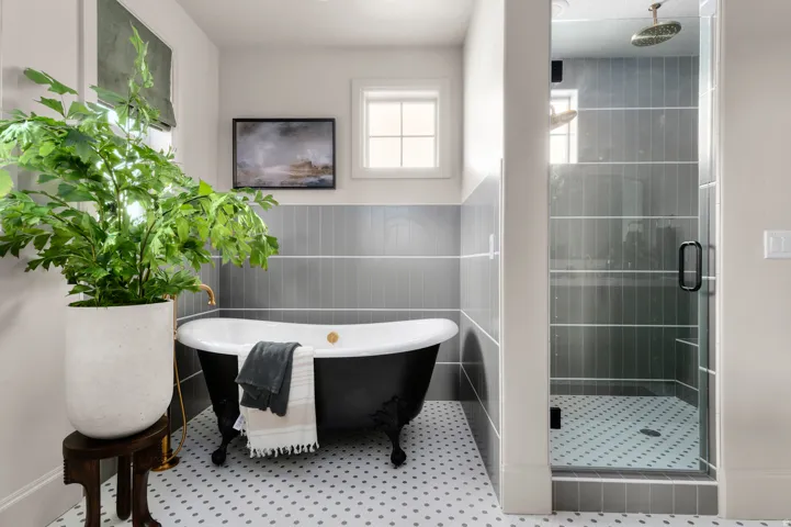 Clawfoot soaking tub, glass-enclosed shower with rain head, and gray subway tile accents