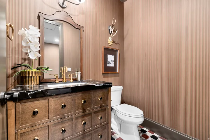 Wood-finish vanity with a black countertop and gold-tone faucet