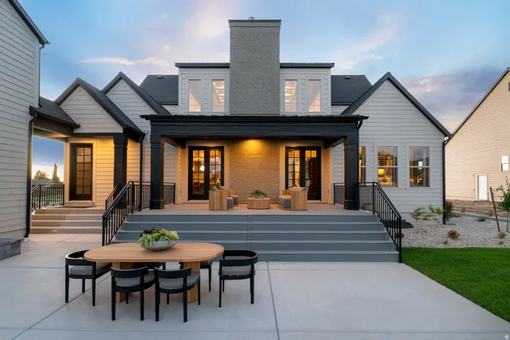 Expansive concrete patio with direct access to a large covered porch featuring a brick wall and dual glass-paned doors