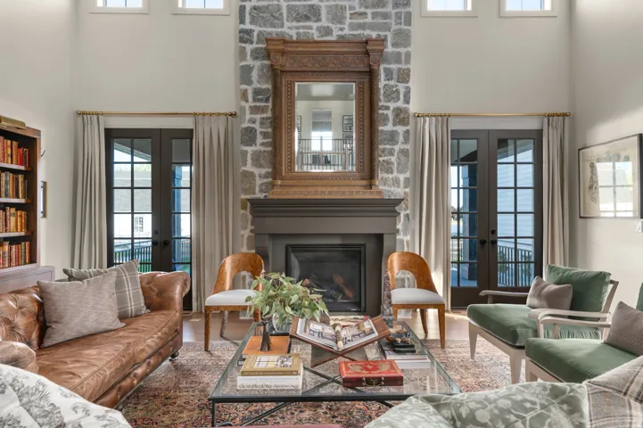 Stone-clad fireplace with a dark wood mantel, flanked by two sets of double French doors