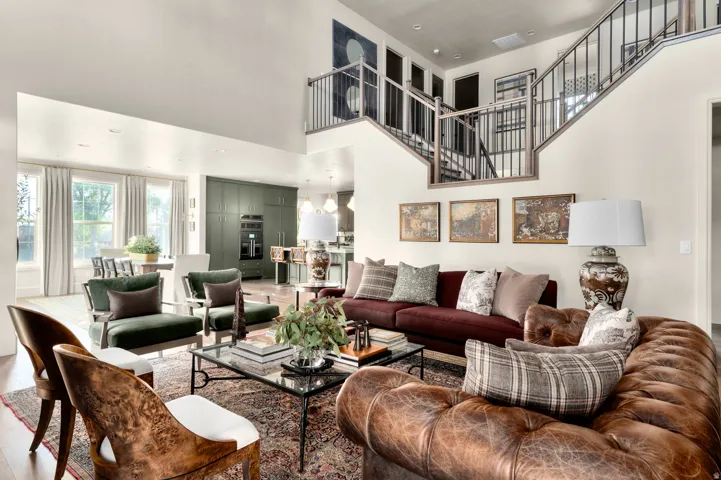 Open-concept living area with high ceilings, wood-finish flooring, a contemporary staircase with metal balusters, and recessed lighting