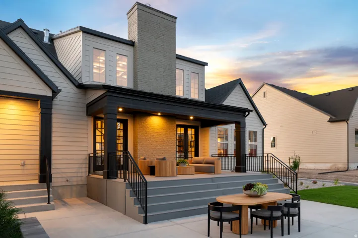 Expansive concrete patio with direct access to a covered deck, featuring black metal railings and overhead lighting