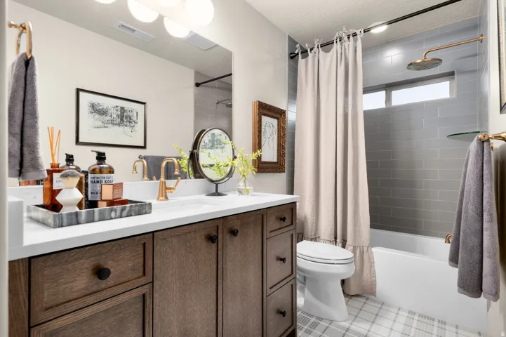 Vanity with wood-finish cabinetry, white countertop, and gold-finish fixtures