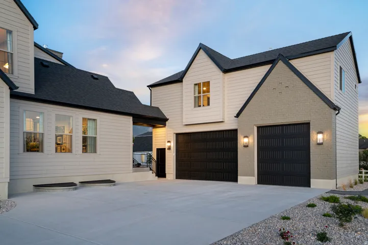 Modern two-car garage with black panel doors and exterior sconce lighting