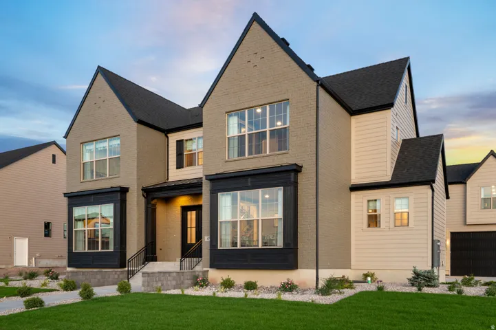 Brick and siding exterior featuring multiple gables, bay windows with dark trim, an inviting covered entry, and a manicured lawn
