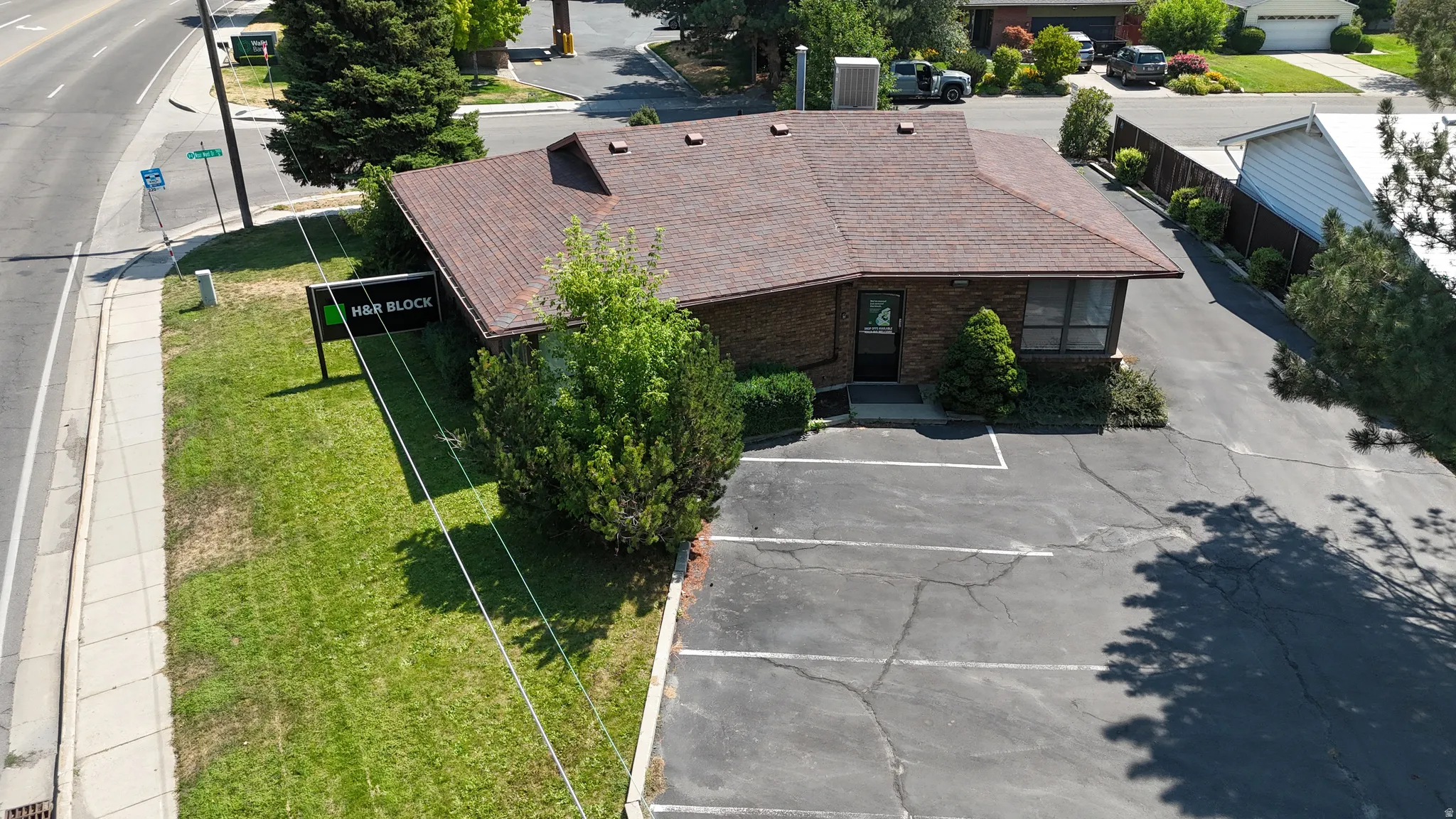 Single-story commercial building with a brown shingle roof, brick exterior, and multiple windows
