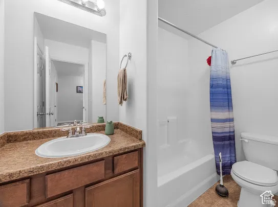 White bathtub and shower combination with a single basin vanity and wood-finish cabinetry