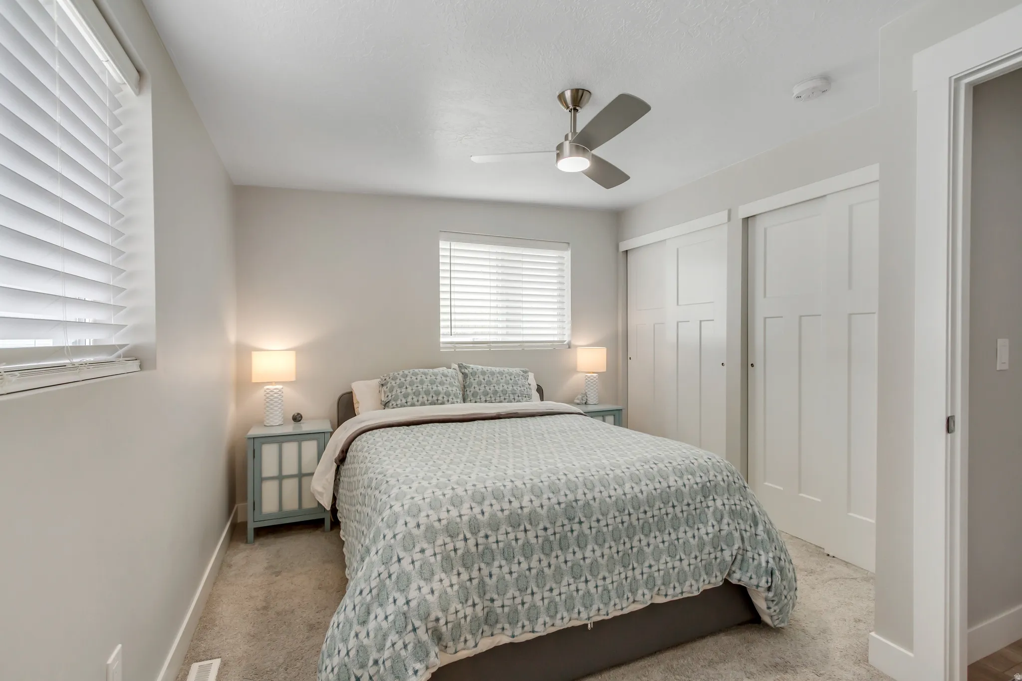 Carpeted flooring, window with blinds, ceiling fan with integrated lighting, and white sliding closet doors