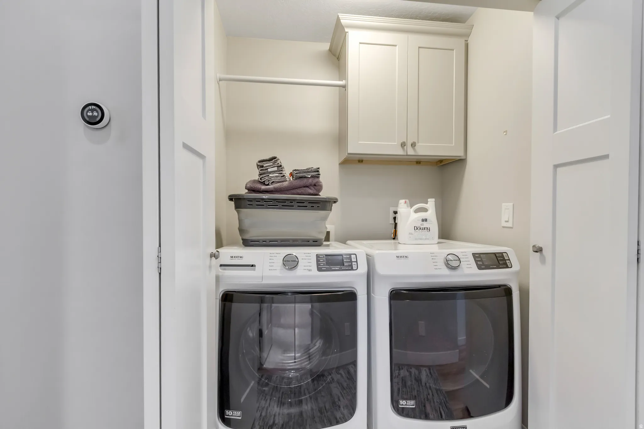 Built-in laundry closet with custom cabinetry, hanging rod, and two appliances