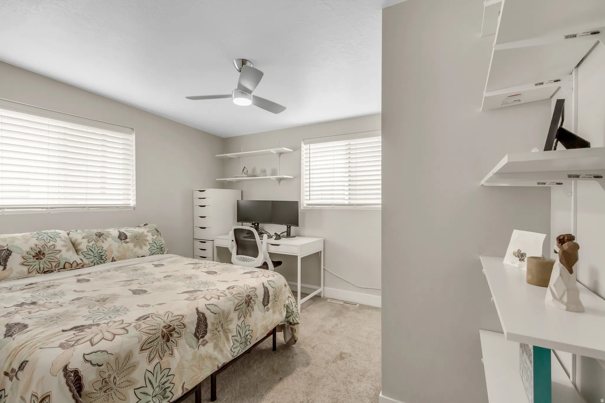 Recessed windows with blinds, ceiling fan, carpeted flooring, and built-in wall shelving