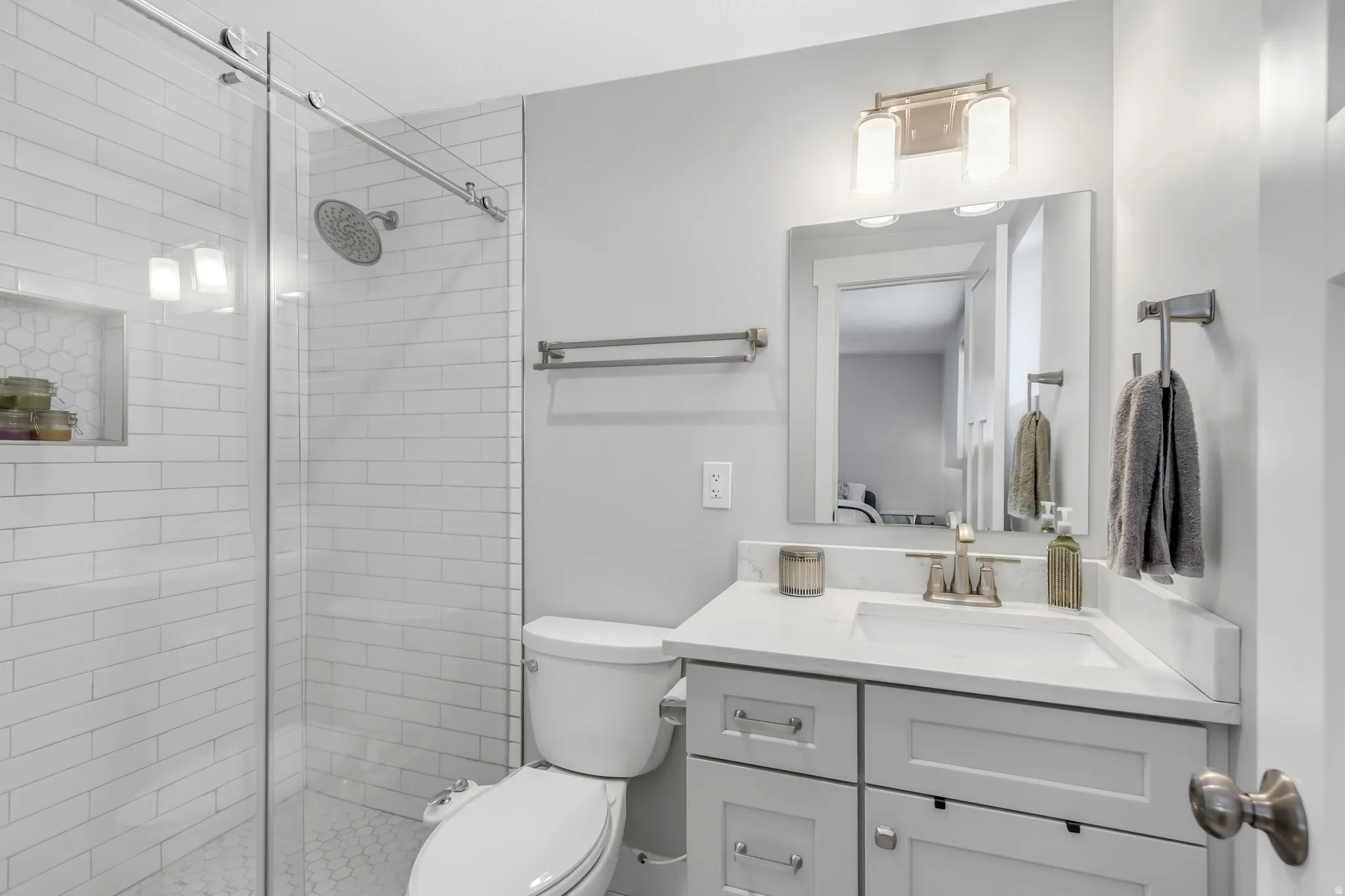 Glass-enclosed shower with subway tile surround and built-in niche