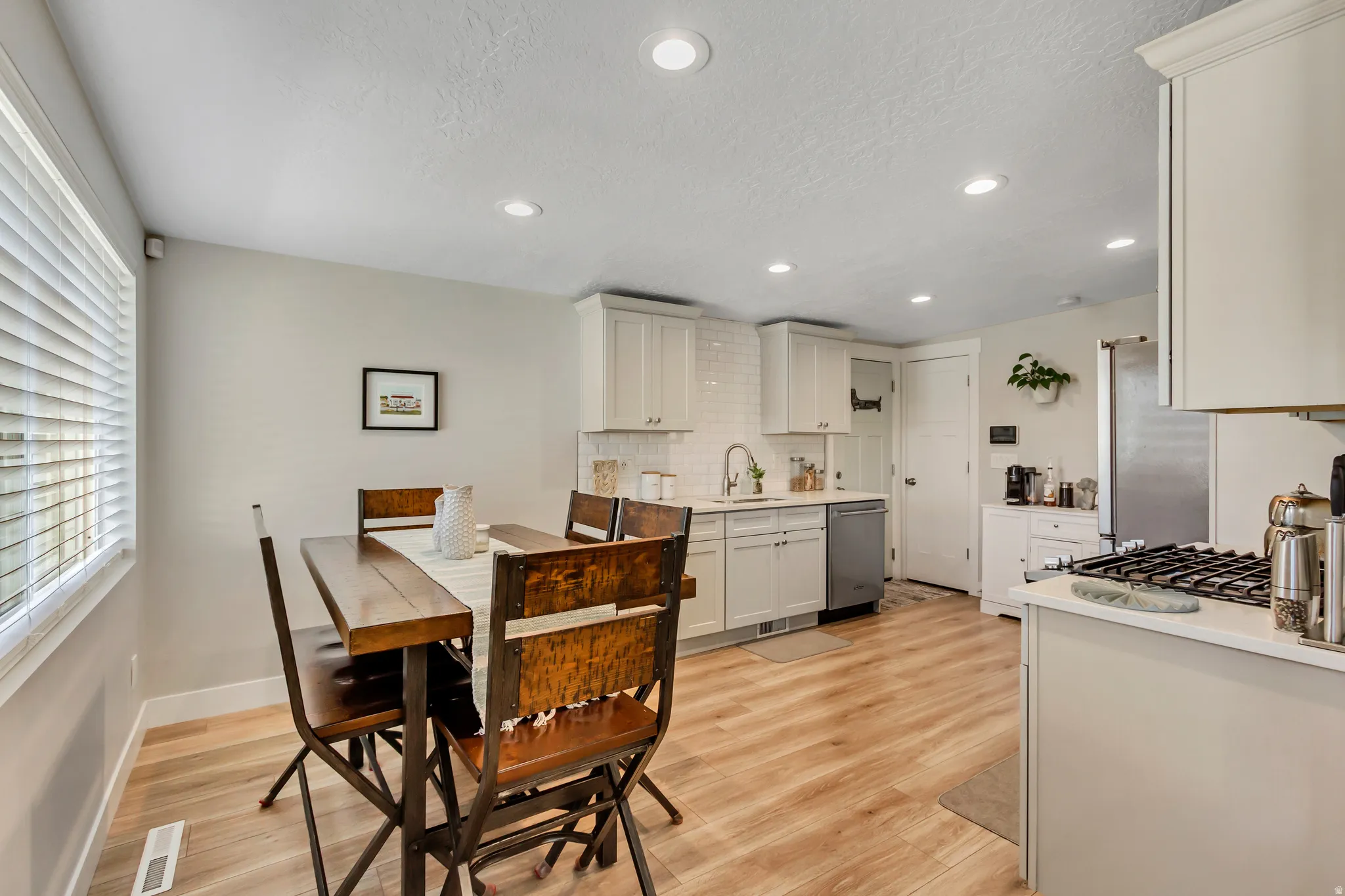 Recessed lighting illuminating the kitchen with wood-finish flooring