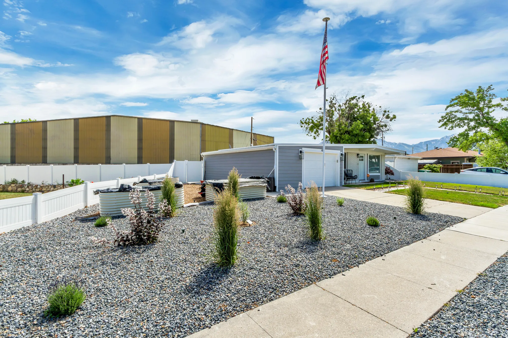 Landscaped front yard with gravel, a concrete walkway, and a white picket fence
