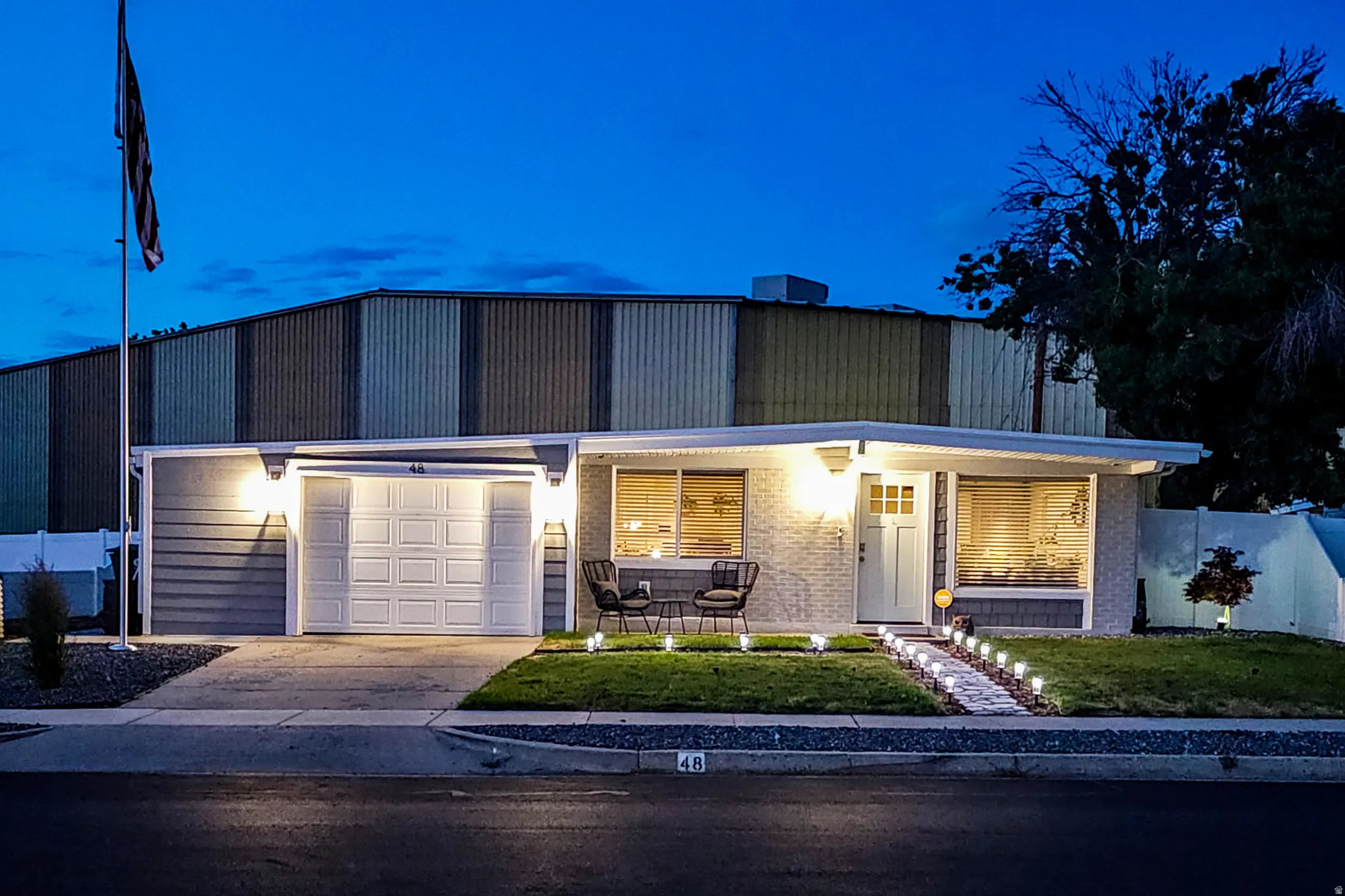Single-story residence featuring a white paneled garage door, light gray siding, and a brick facade