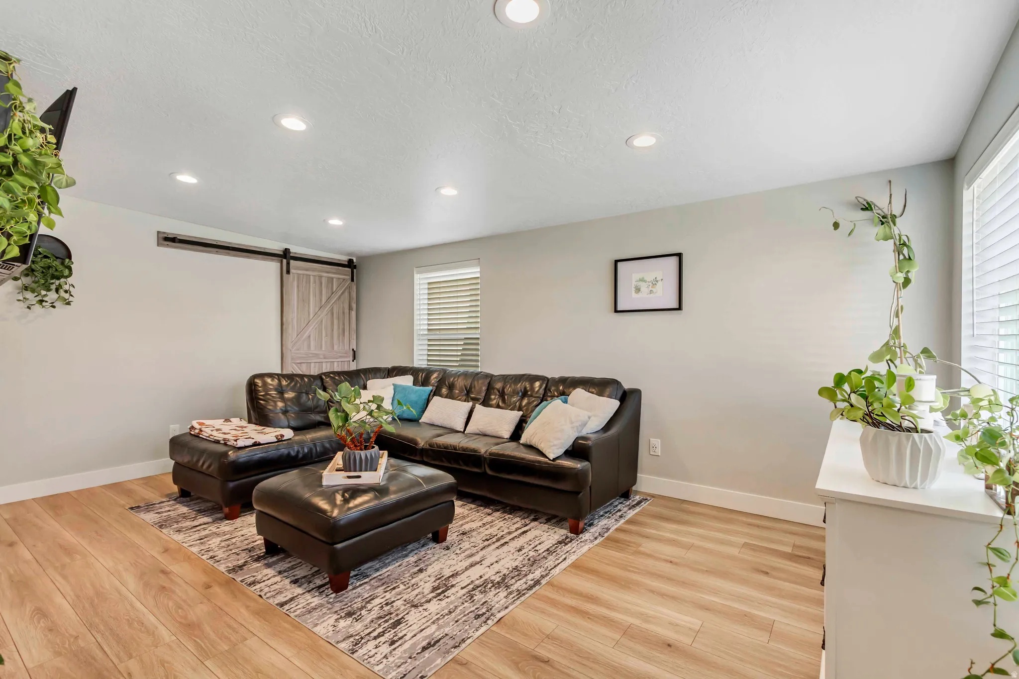 Recessed ceiling lighting, wood-finish flooring, and a barn door entry